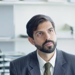 The Ethics of Addiction: Why Leaders Must Master Biological Control Thoughtful businessman in suit and tie in modern office environment.