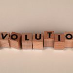 Wooden blocks spelling 'Evolution' on a neutral beige background, symbolizing change and growth.