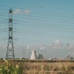Scenic view of high voltage towers and power plant against a clear sky over dry grassland.