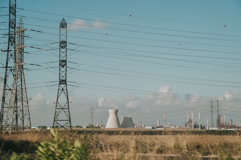 Scenic view of high voltage towers and power plant against a clear sky over dry grassland.