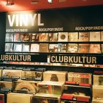 A vibrant indie music store displaying a variety of vinyl records under the categories rock, pop, and club culture.