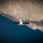 <h1>The Few-Shot On-Orbit Manufacturing Compiler: Revolutionizing Space Supply Chains</h1> A satellite hovering above Earth's coastline, captured from space.