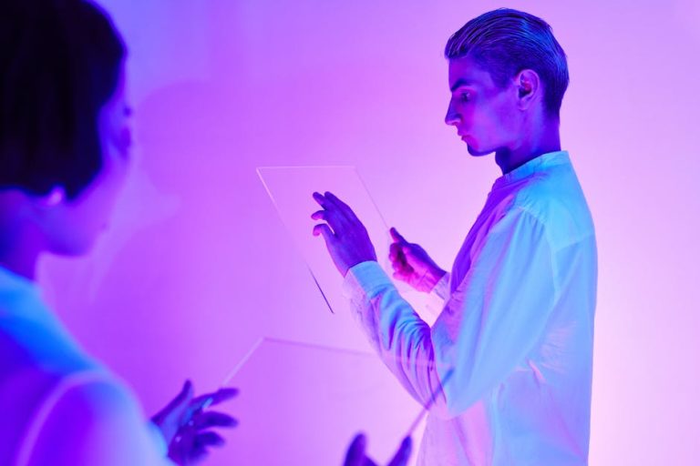 Two individuals engaging with futuristic transparent touch screens in a vibrant purple-lit studio.
