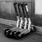 <h1>The Future of Mobility: Building Privacy-Preserving Carbon Removal Toolchains for Autonomous Vehicles</h1> A group of electric scooters parked against a building wall, highlighting urban transportation.