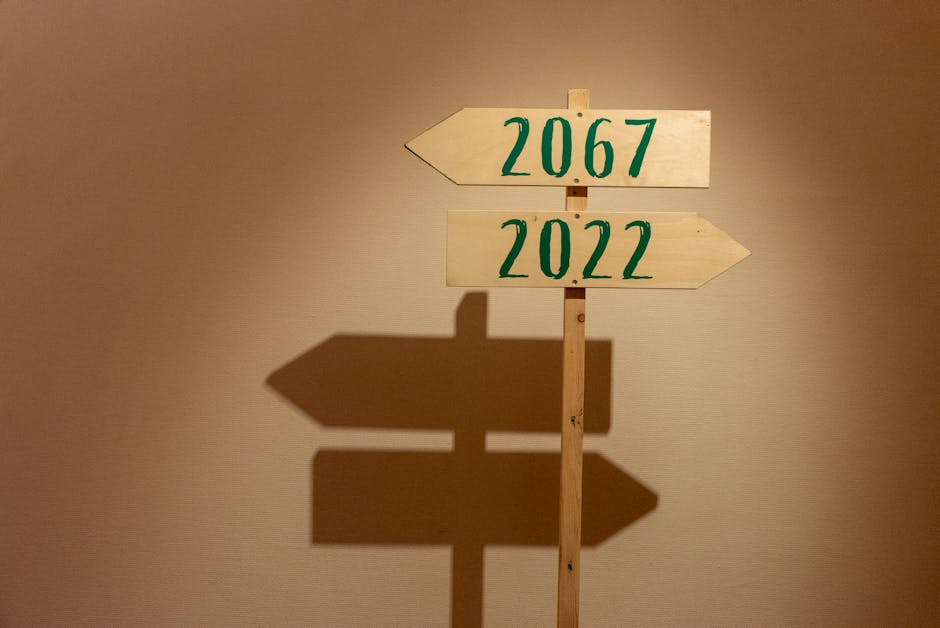 Wooden signpost indoors pointing to years 2067 and 2022, casting shadows.