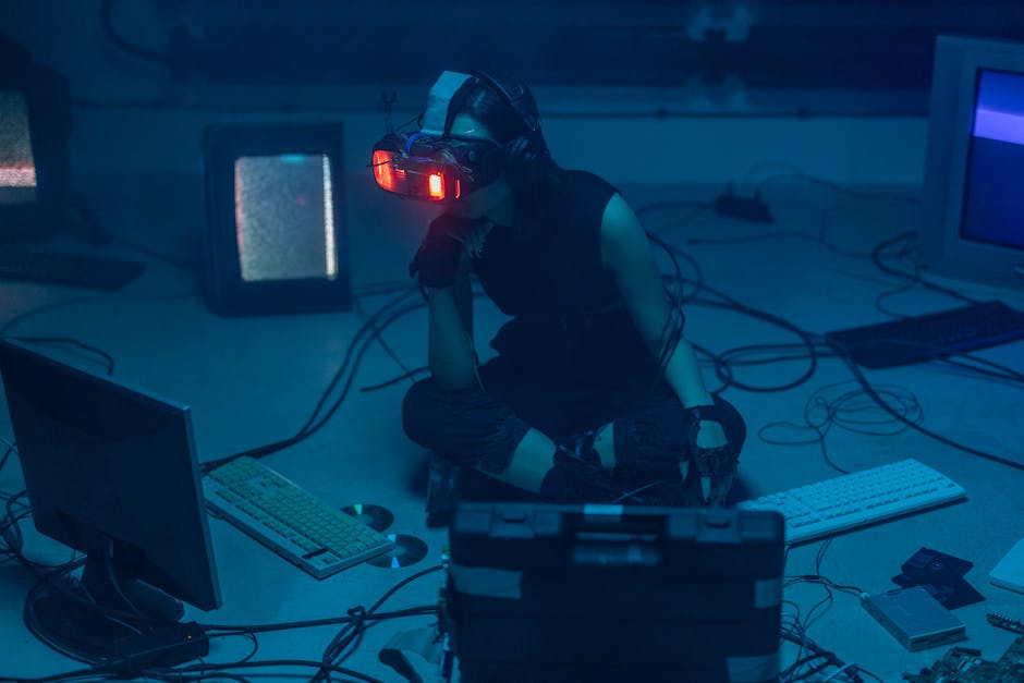 A woman in a dark room wearing a VR headset surrounded by retro technology.