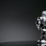 Compact humanoid robot toy standing on a reflective surface, exuding a futuristic vibe.