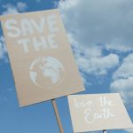 <h1>The Future of Sustainability: Building a Few-Shot Carbon Removal Compiler for Supply Chains</h1> Protest signs promoting environmental conservation against a cloudy blue sky.