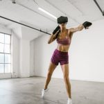 The Future of Wellness: Precision Strategy for High-Performance Leaders A woman engaging in a workout session using a VR headset indoors, promoting fitness and technology synergy.