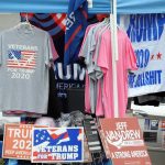 The Gerontocracy Trap: Why Political Longevity Stalls Strategic Execution A stall displaying Trump 2020 merchandise including shirts and signs at an outdoor market.