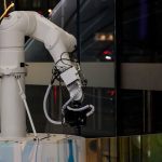 The Ghost in the Machine: AI and the Future of Conscious Leadership A white robotic arm operating indoors with a modern design and advanced technology.