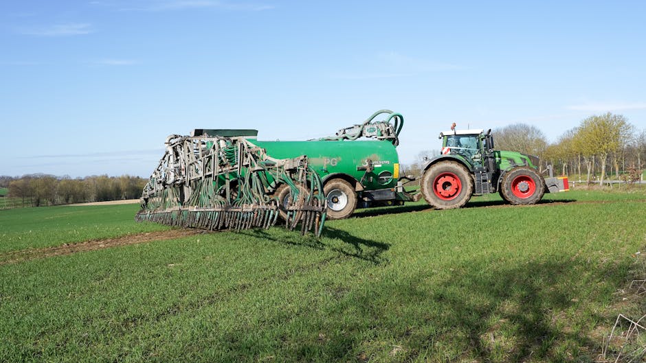 Tractor and manure spreader on green farmland in Lütau, Schleswig-Holstein, Germany.
