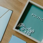 The High Cost of Political Burnout: Why Mental Health Defines Governance Top view of a box with 'POLITICS' text alongside office items on a wooden desk.