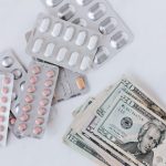 The High Cost of Wellness Data Privacy for Executive Performance Top view of different blisters of medications and pills composed with heap of paper money