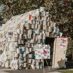 Unique architectural structure made entirely of books, showcasing creativity and literature in an urban outdoor location.