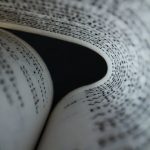 Artistic close-up of book pages forming a curve, showcasing detailed text patterns.