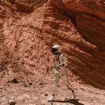 The Longevity Frontier: Futurist Strategies for Human Capital An astronaut in a space suit explores a Mars-like desert landscape, showcasing exploration and adventure.