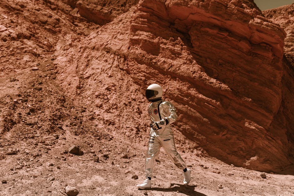 An astronaut in a space suit explores a Mars-like desert landscape, showcasing exploration and adventure.