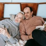 The Media Ecosystem: How Relationships Drive Strategic Advantage High angle of happy adult woman using tablet and cuddling with ethnic husband reading interesting book on bed at home