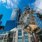 Captivating view of New York City skyline featuring a prominent globe sculpture and tall skyscrapers.