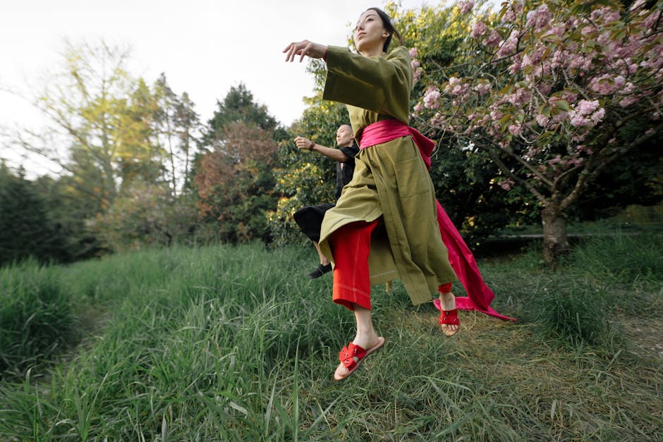 Two people dancing joyfully in traditional wear surrounded by cherry blossoms in a serene Japanese garden.