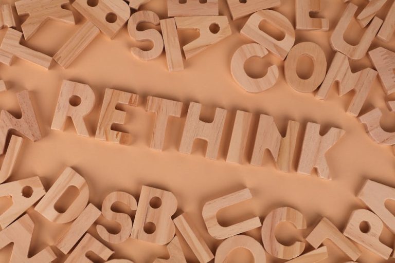 Wooden alphabet letters forming the word rethink on a flat, peach-colored background.
