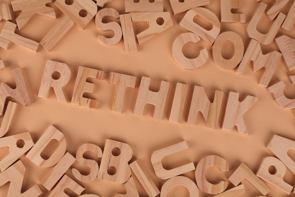Wooden alphabet letters forming the word rethink on a flat, peach-colored background.