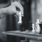 Black and white image capturing a strategic chess move with a wooden chessboard in Eskişehir.