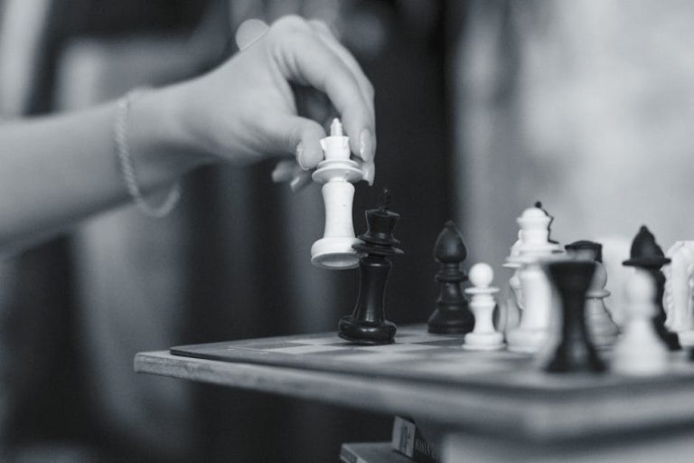 Black and white image capturing a strategic chess move with a wooden chessboard in Eskişehir.