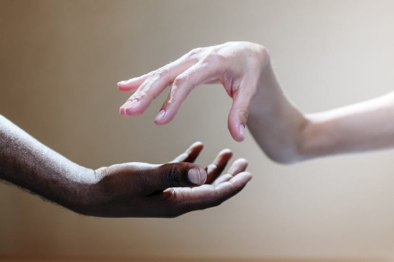 Two people reaching out, symbolizing unity and diversity through the touch of hands.