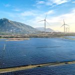 Aerial view of a solar and wind energy farm set against Vietnam's scenic landscape.