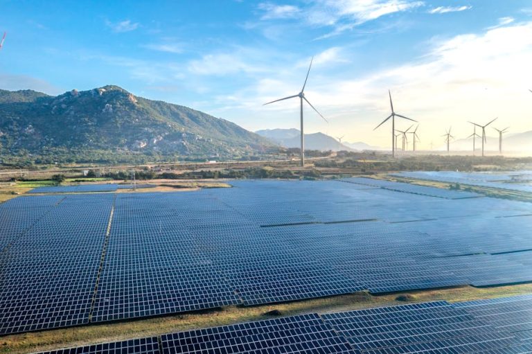 Aerial view of a solar and wind energy farm set against Vietnam's scenic landscape.