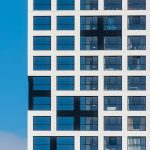 Close-up view of a modern building facade with grid windows against a clear blue sky.