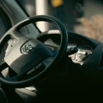 Detailed interior view of a vehicle showcasing the steering wheel and dashboard elements in soft lighting.