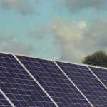 Photograph of solar panels capturing renewable energy under a blue sky, promoting sustainability and environmental protection.