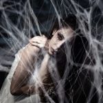 The Spiritual Trap: Why High-Performers Become Addicted to Enlightenment Mysterious woman trapped in spiderwebs creating a Halloween-themed eerie atmosphere.