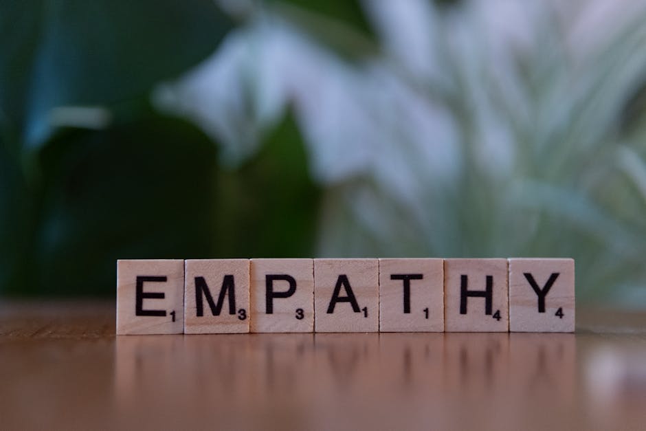 Close-up of tiles spelling empathy on a wooden surface with blurred green background.