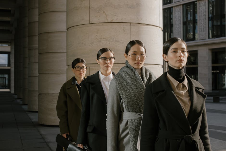 Group of professional women in elegant business attire posing outdoors in urban setting.