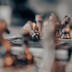 A focused artistic close-up of chess pieces on a board, featuring a fallen king, captured with shallow focus.