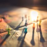 A close-up view of colorful push pins casting shadows on a world map during sunset, highlighting global travel.