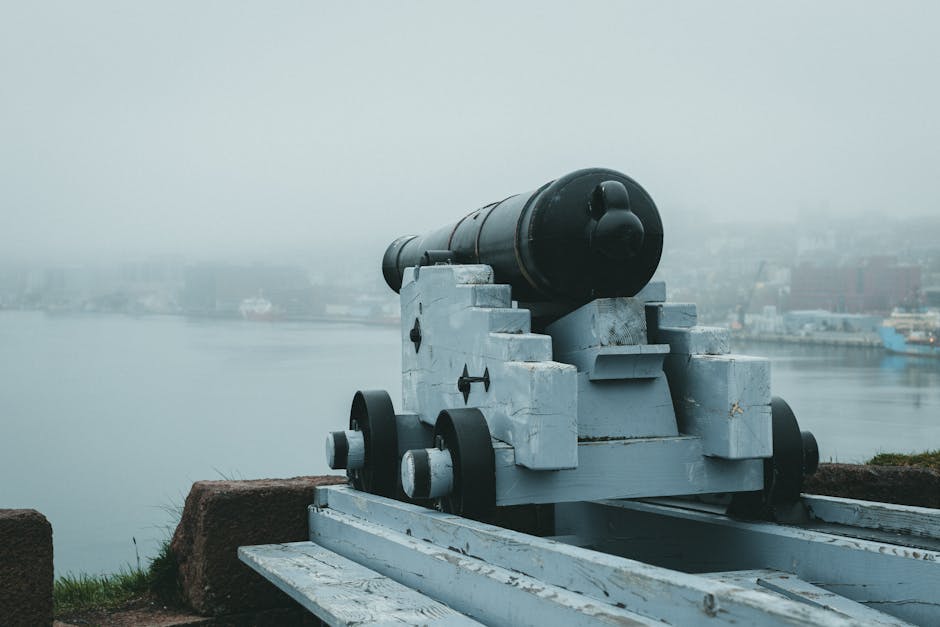A historic cannon aimed at the misty seaside from a fortress, evoking a sense of defense and history.