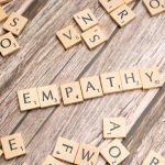Wooden letter tiles spelling 'empathy' on a wooden background conveying connection.