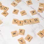 The Strategic Health Dividend: How Renewable Energy Impacts Outcomes Scrabble tiles forming the word 'YIELD' on a marble surface, symbolizing finance and investment.