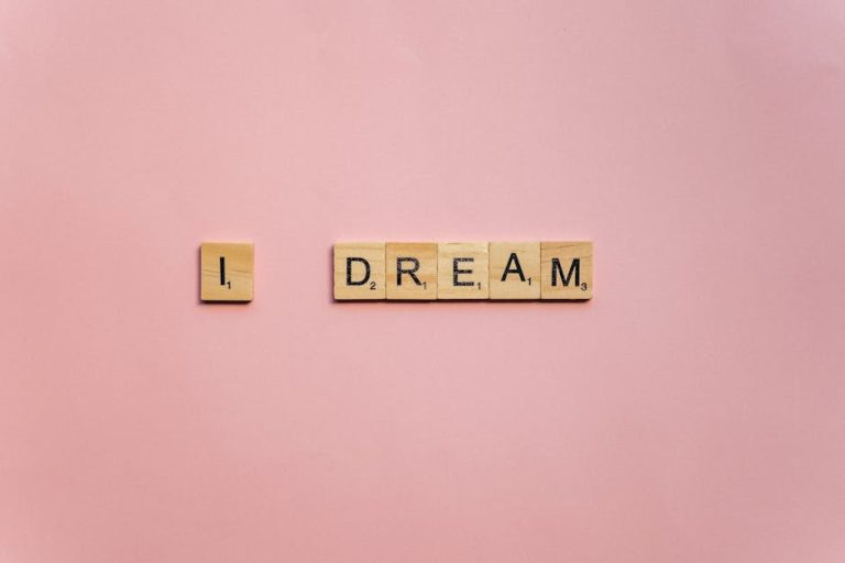 Scrabble tiles spelling 'I Dream' on a soft pink background for motivation.