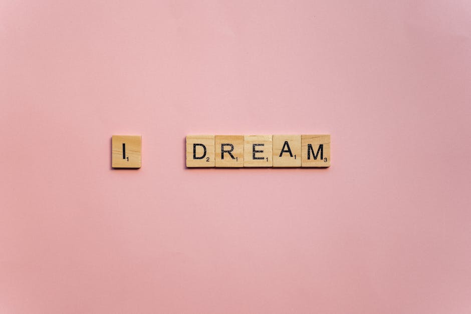 Scrabble tiles spelling 'I Dream' on a soft pink background for motivation.
