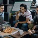 The Strategic History of Food Security: Lessons for Future Survival Group of young men having pizza and discussing ideas during a startup meeting in a casual setting.