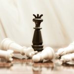 The Strategic Power of Privacy: Historical Lessons for Leaders A black chess queen stands triumphant among toppled white pieces on a reflective surface.