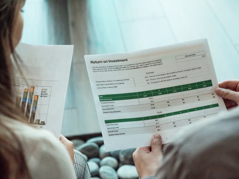 Close-up of two individuals analyzing financial documents related to return on investment.