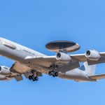 The Strategic Role of Surveillance in Scientific Advancement A military AWACS aircraft flying against a clear blue sky, showcasing aerial surveillance capabilities.