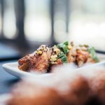The Strategic Shift: How Food Security Redefines Modern Culture Appetizing roasted chicken wings decorated with parsley and corn served on white plate on table in restaurant on blurred background